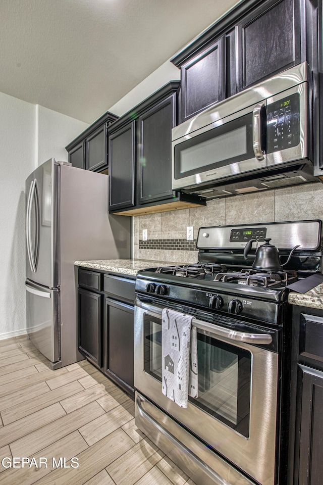 7517 Red Cedar Dr, El Paso, TX 79911 - kitchen with appliances with stainless steel finishes, tasteful backsplash, light wood-style flooring, baseboards, and light stone countertops