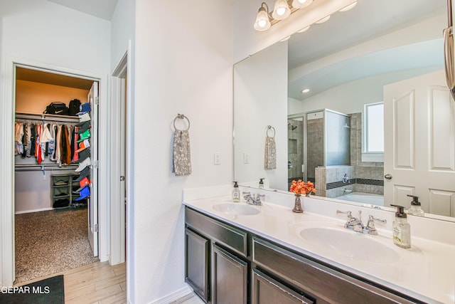 7517 Red Cedar Dr, El Paso, TX 79911 - bathroom featuring a stall shower, a walk in closet, a bath, double vanity, and wood finished floors