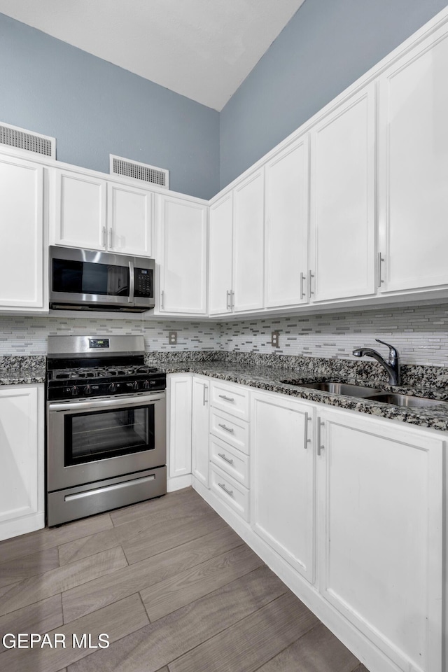 3899 Vanderveer Dr Unit A B C, El Paso, TX 79938 - kitchen featuring appliances with stainless steel finishes, a sink, decorative backsplash, white cabinets, and dark stone counters