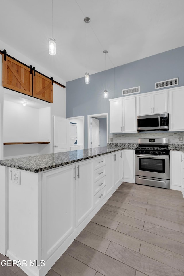 3899 Vanderveer Dr Unit A B C, El Paso, TX 79938 - kitchen featuring stainless steel appliances, dark stone counters, white cabinetry, and decorative light fixtures