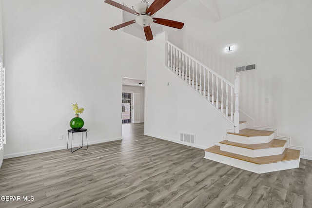 6929 Canyon View Ln, El Paso, TX 79912 - unfurnished living room featuring a towering ceiling, stairs, wood finished floors, a ceiling fan, and baseboards