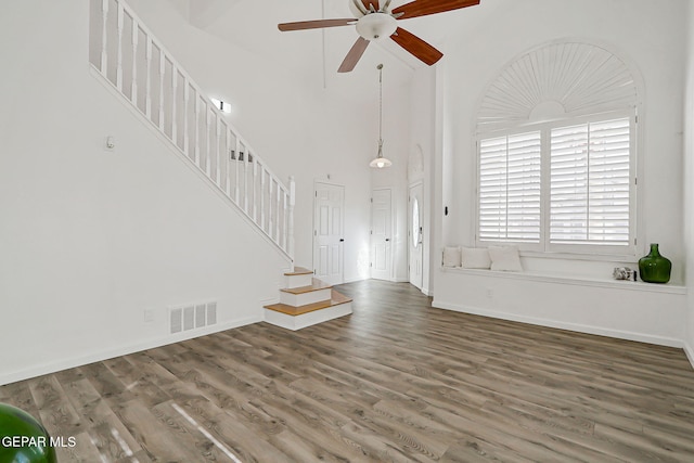 6929 Canyon View Ln, El Paso, TX 79912 - unfurnished living room with stairs, ceiling fan, wood finished floors, a high ceiling, and baseboards