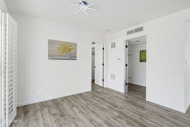 6929 Canyon View Ln, El Paso, TX 79912 - unfurnished bedroom featuring a walk in closet, light wood finished floors, baseboards, a textured ceiling, and a closet