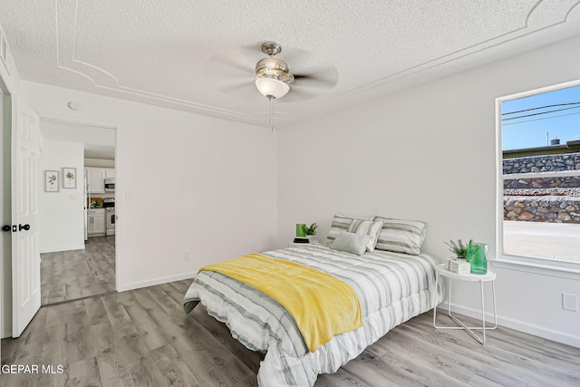 6929 Canyon View Ln, El Paso, TX 79912 - bedroom with a textured ceiling, light wood-style floors, baseboards, and a ceiling fan