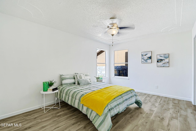 6929 Canyon View Ln, El Paso, TX 79912 - bedroom featuring wood finished floors, a textured ceiling, baseboards, and ceiling fan
