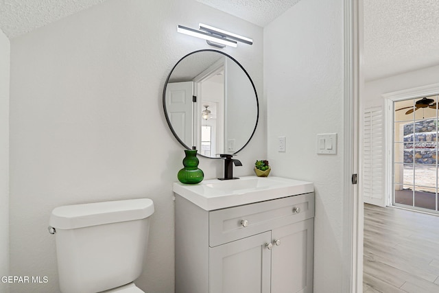 6929 Canyon View Ln, El Paso, TX 79912 - half bathroom with a textured ceiling, toilet, vanity, and wood finished floors