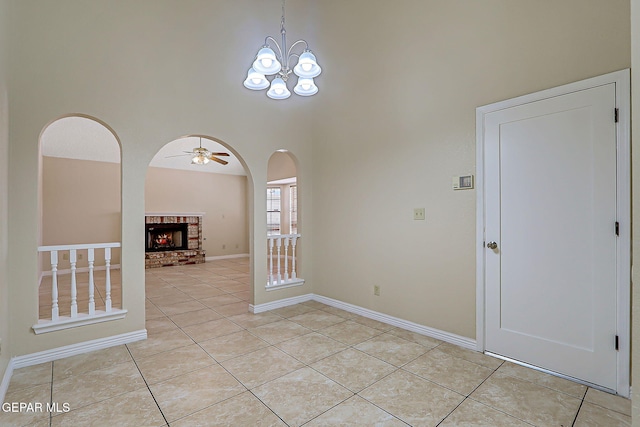 12013 Meadow Gate Dr, El Paso, TX 79936 - spare room with light tile patterned floors, a towering ceiling, a ceiling fan, a brick fireplace, and arched walkways