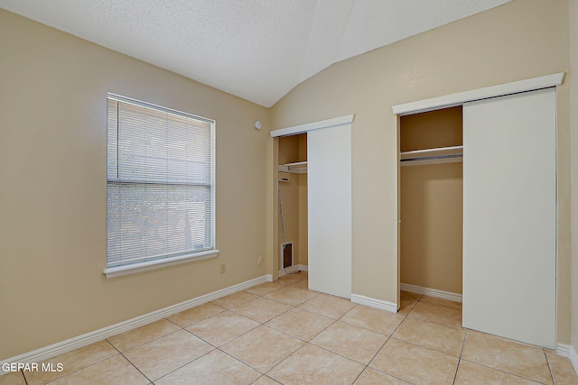 12013 Meadow Gate Dr, El Paso, TX 79936 - unfurnished bedroom with multiple closets, light tile patterned floors, baseboards, and lofted ceiling