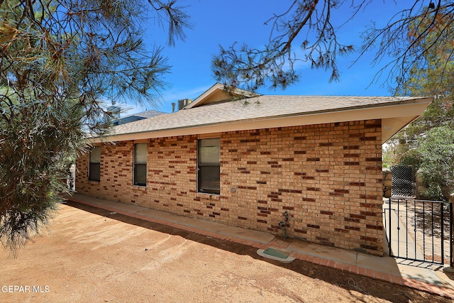12013 Meadow Gate Dr, El Paso, TX 79936 - view of side of property featuring brick siding and roof with shingles