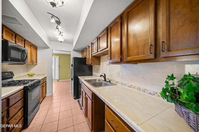 500 Tawny Oaks Pl, El Paso, TX 79912 - kitchen featuring black appliances, a sink, backsplash, light tile patterned floors, and brown cabinets