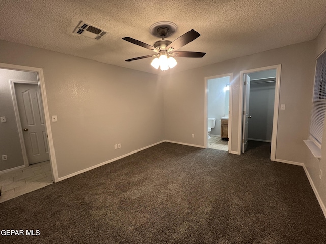 10256 Valle Suave Dr, El Paso, TX 79927 - unfurnished bedroom with dark colored carpet, a spacious closet, baseboards, a textured ceiling, and ensuite bath
