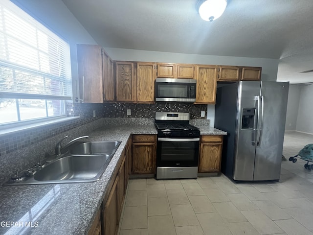 10256 Valle Suave Dr, El Paso, TX 79927 - kitchen with stainless steel appliances, decorative backsplash, a sink, and brown cabinetry