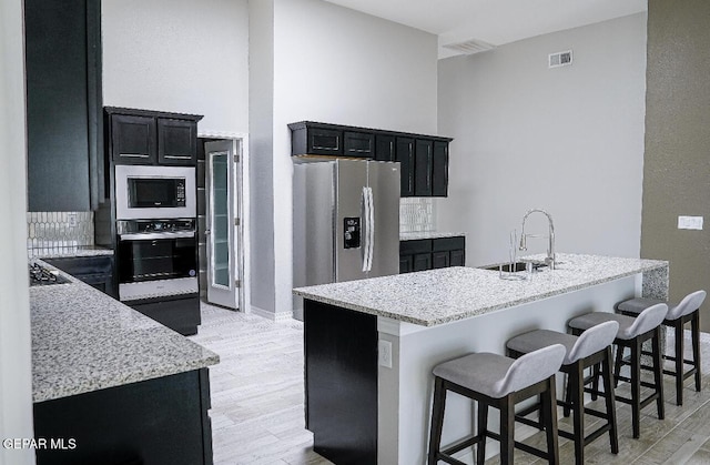 3920 Aspiration St, El Paso, TX 79938 - kitchen with stainless steel appliances, dark cabinetry, light wood finished floors, and a breakfast bar