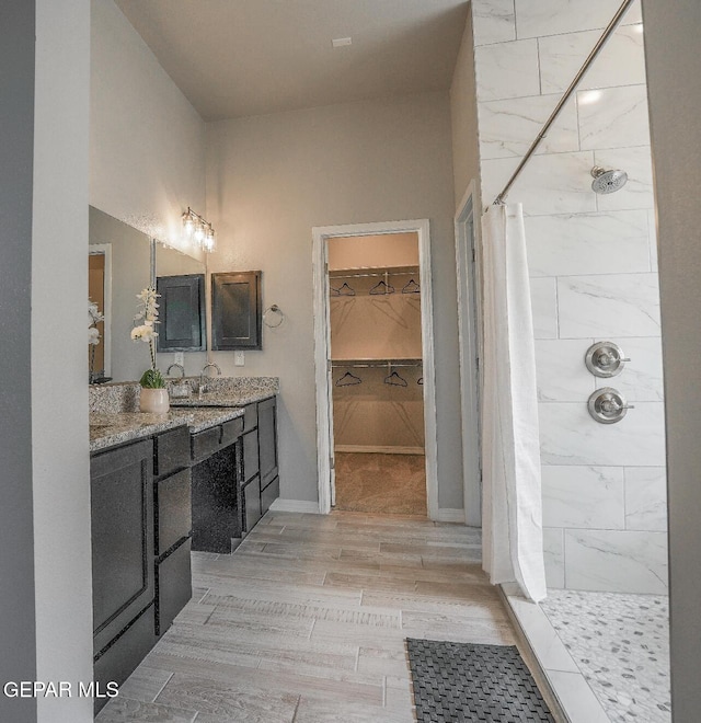 3920 Aspiration St, El Paso, TX 79938 - bathroom featuring vanity, tiled shower, a spacious closet, and wood finished floors