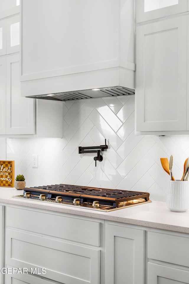 13380 Coldham St, El Paso, TX 79928 - kitchen featuring decorative backsplash, white cabinets, stainless steel gas cooktop, premium range hood, and glass insert cabinets