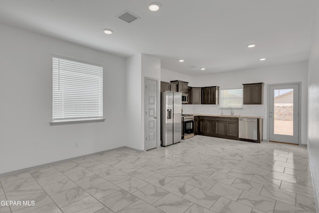 15221 Apex Ct, El Paso, TX 79938 - kitchen featuring appliances with stainless steel finishes, dark brown cabinets, light countertops, recessed lighting, and light marble finish flooring