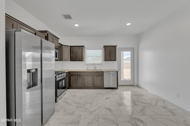 15221 Apex Ct, El Paso, TX 79938 - kitchen with stainless steel appliances, dark brown cabinets, light marble finish flooring, recessed lighting, and light stone countertops