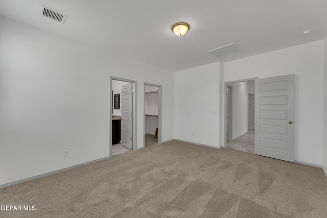 15221 Apex Ct, El Paso, TX 79938 - unfurnished bedroom featuring a walk in closet, light carpet, ensuite bathroom, and a closet