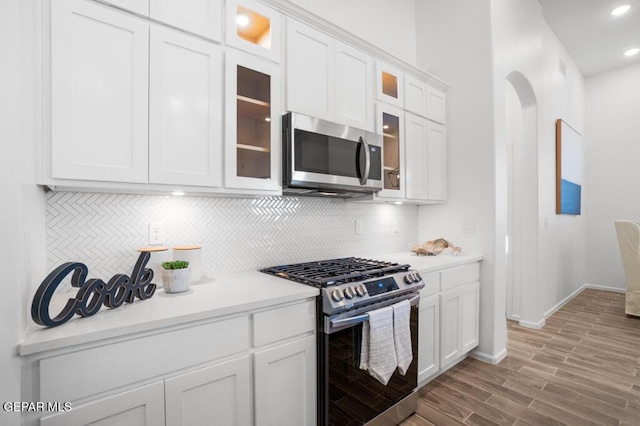 891 Dewsbury Way, El Paso, TX 79928 - kitchen with appliances with stainless steel finishes, arched walkways, backsplash, white cabinets, and light countertops