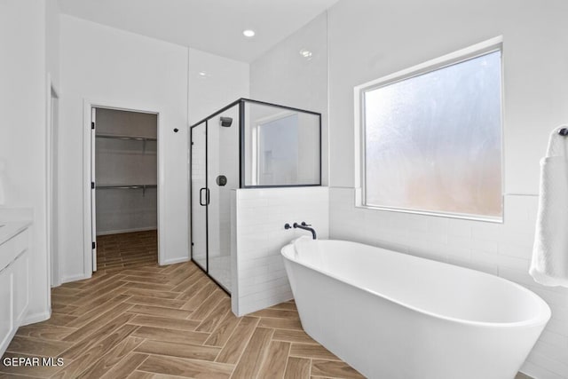 891 Dewsbury Way, El Paso, TX 79928 - bathroom featuring a shower stall, a walk in closet, a freestanding bath, vanity, and tile walls