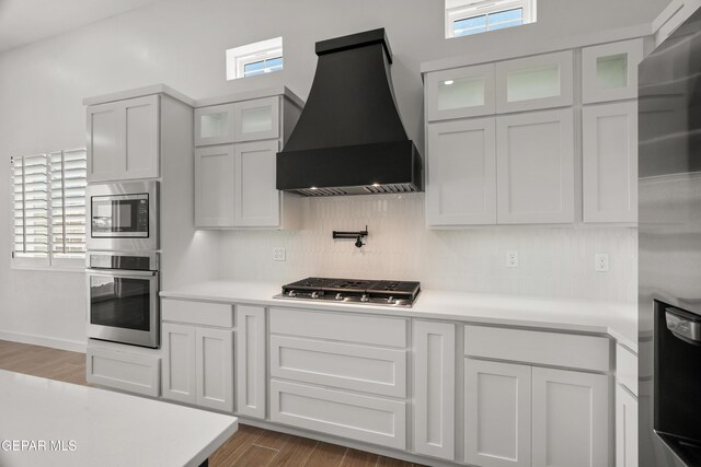 895 Dewsbury Way, El Paso, TX 79928 - kitchen with appliances with stainless steel finishes, premium range hood, light countertops, wood finished floors, and tasteful backsplash
