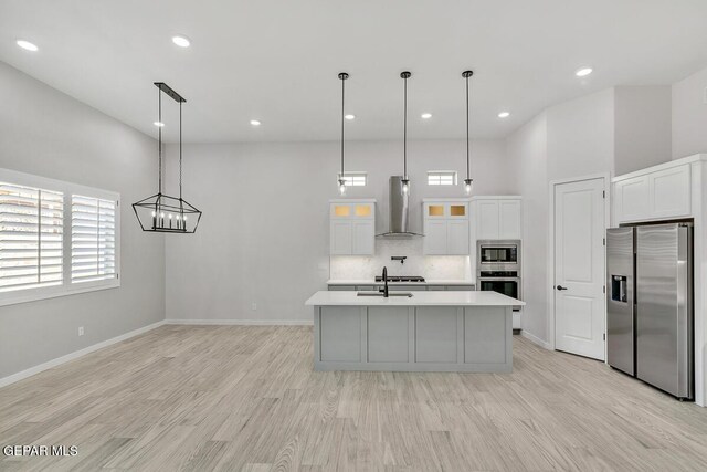 899 Dewsbury Way, El Paso, TX 79928 - kitchen featuring appliances with stainless steel finishes, wall chimney exhaust hood, light countertops, a sink, and light wood-style flooring