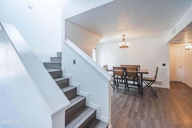 7573 Le Conte Dr Unit A, El Paso, TX 79912 - staircase featuring wood finished floors, a textured ceiling, baseboards, and a chandelier
