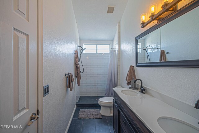 7573 Le Conte Dr Unit A, El Paso, TX 79912 - bathroom featuring a textured wall, tile patterned flooring, toilet, a tile shower, and double vanity