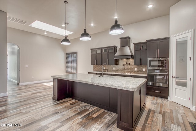 1857 War Path Dr, El Paso, TX 79911 - kitchen featuring stainless steel appliances, a sink, custom exhaust hood, arched walkways, and backsplash