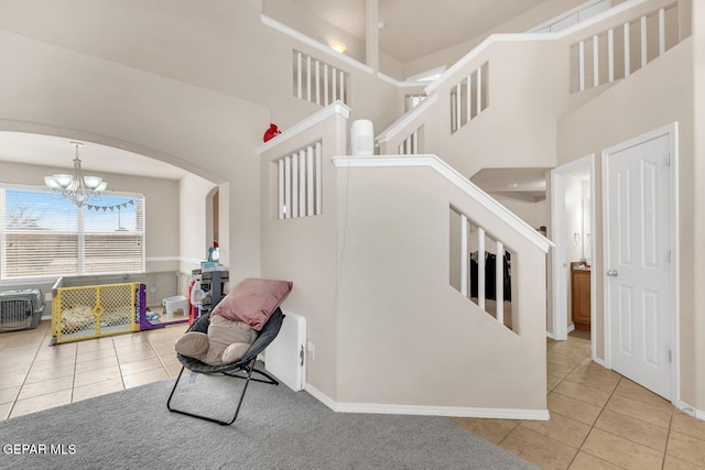 7101 Mesquite Tree Ln, El Paso, TX 79934 - staircase with tile patterned flooring, a towering ceiling, arched walkways, a chandelier, and baseboards