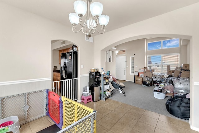 7101 Mesquite Tree Ln, El Paso, TX 79934 - carpeted dining space featuring arched walkways, tile patterned flooring, a chandelier, and a wainscoted wall
