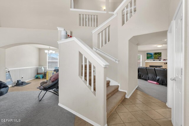 7101 Mesquite Tree Ln, El Paso, TX 79934 - stairway featuring arched walkways, carpet floors, a chandelier, tile patterned flooring, and a towering ceiling