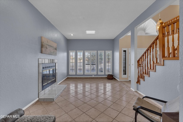 6101 Via Suerte Ave, El Paso, TX 79912 - unfurnished living room featuring a textured wall, tile patterned floors, baseboards, a fireplace, and stairway