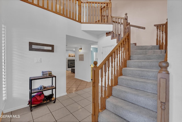 6101 Via Suerte Ave, El Paso, TX 79912 - staircase with tile patterned floors, baseboards, a tile fireplace, and a high ceiling