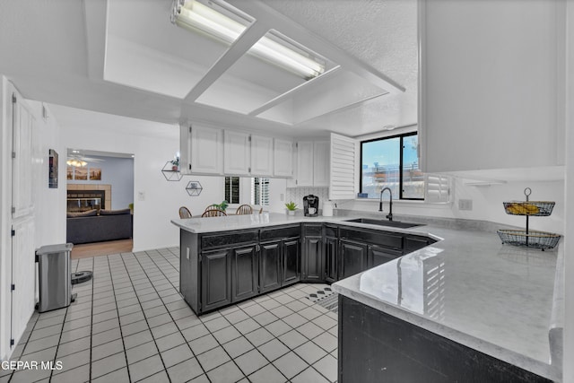 6101 Via Suerte Ave, El Paso, TX 79912 - kitchen with a sink, dark cabinetry, a peninsula, white cabinetry, and light tile patterned floors