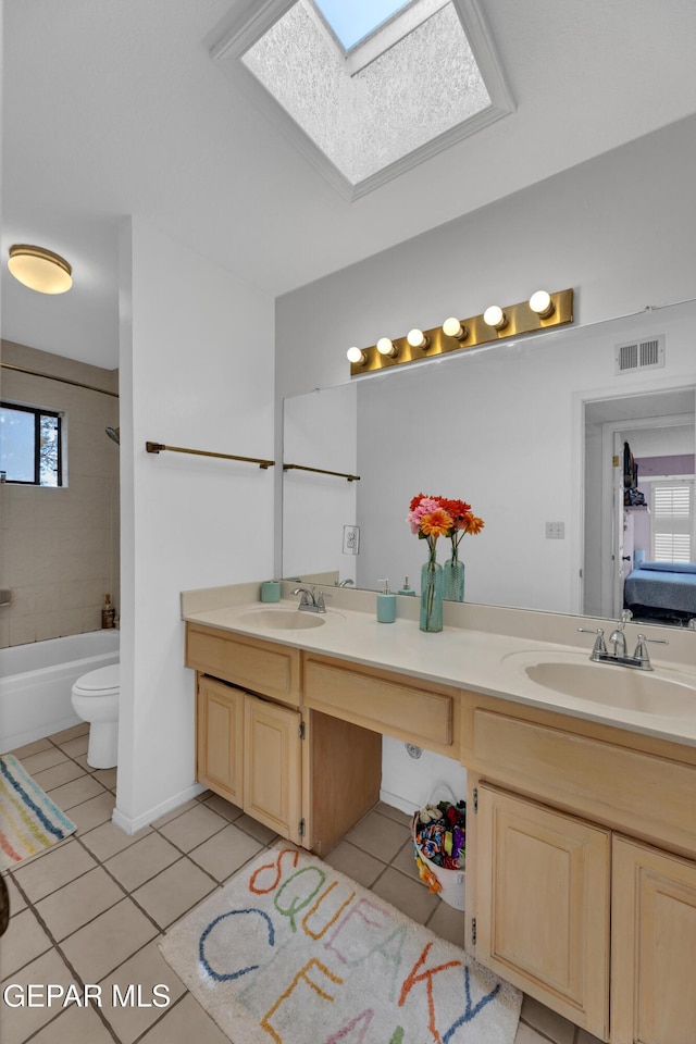 6101 Via Suerte Ave, El Paso, TX 79912 - full bath with tile patterned floors, double vanity, a skylight, toilet, and shower / bath combination