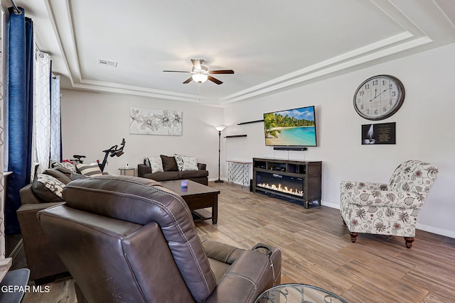 12749 Iron Falls Dr, Horizon City, TX 79928 - living room with a tray ceiling, a ceiling fan, wood finished floors, baseboards, and a glass covered fireplace