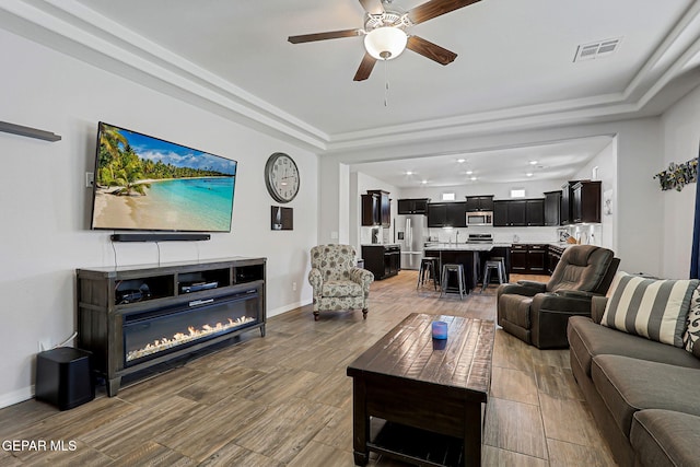 12749 Iron Falls Dr, Horizon City, TX 79928 - living area featuring a ceiling fan, a tray ceiling, wood finished floors, baseboards, and recessed lighting