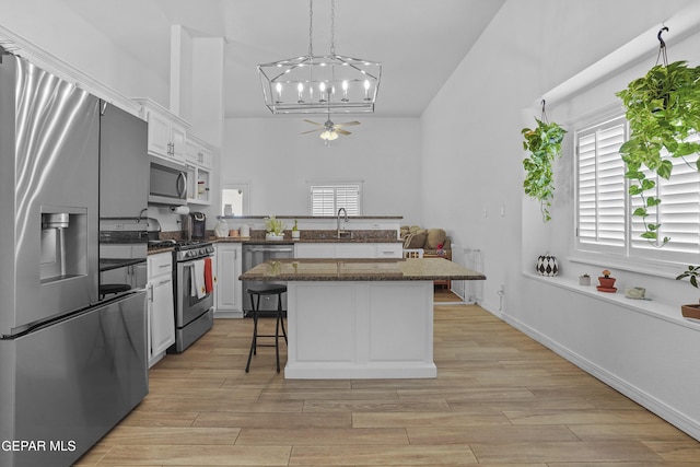 11973 Regal Banner Ln, El Paso, TX 79936 - kitchen with appliances with stainless steel finishes, a chandelier, light wood-type flooring, a breakfast bar area, and a center island