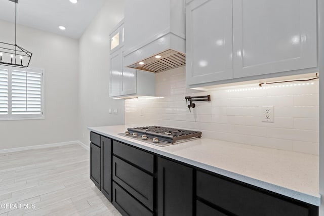 13351 Jeff Winton Dr, El Paso, TX 79928 - kitchen featuring custom range hood, stainless steel gas cooktop, decorative backsplash, baseboards, and light stone countertops