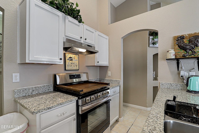 11840 Balladeer Ave, El Paso, TX 79936 - kitchen featuring stainless steel range, under cabinet range hood, arched walkways, light tile patterned floors, and white cabinets