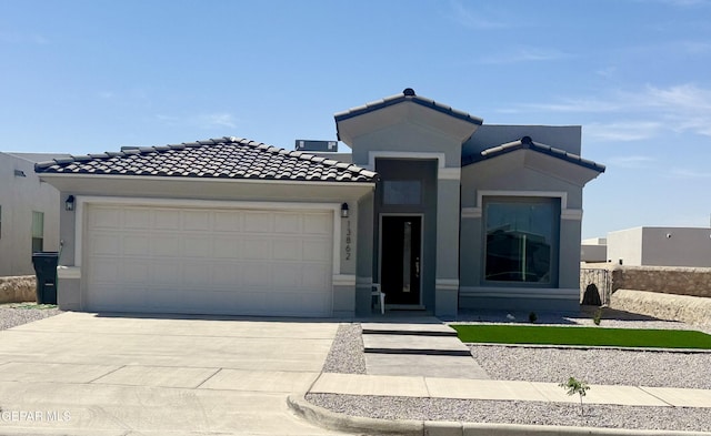 13862 Paseo Bosque Ave, El Paso, TX 79928 - view of front of home with an attached garage, driveway, a tiled roof, and stucco siding