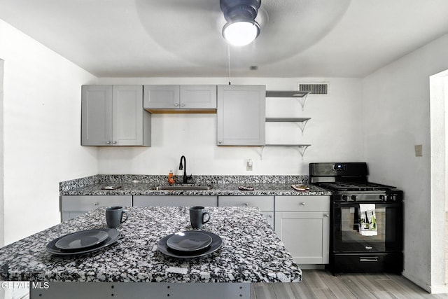 264 Edith Dr, El Paso, TX 79915 - kitchen with black gas range, gray cabinetry, light wood-style flooring, open shelves, and dark stone counters