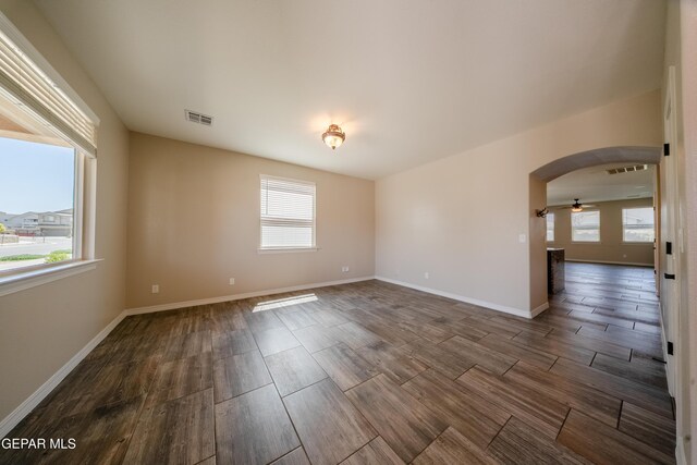 12320 Desert Path Ct, El Paso, TX 79938 - empty room with dark wood-style flooring, arched walkways, and healthy amount of natural light