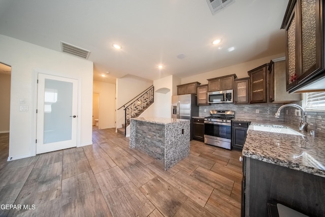 12320 Desert Path Ct, El Paso, TX 79938 - kitchen with appliances with stainless steel finishes, a sink, light wood finished floors, a center island, and stone countertops
