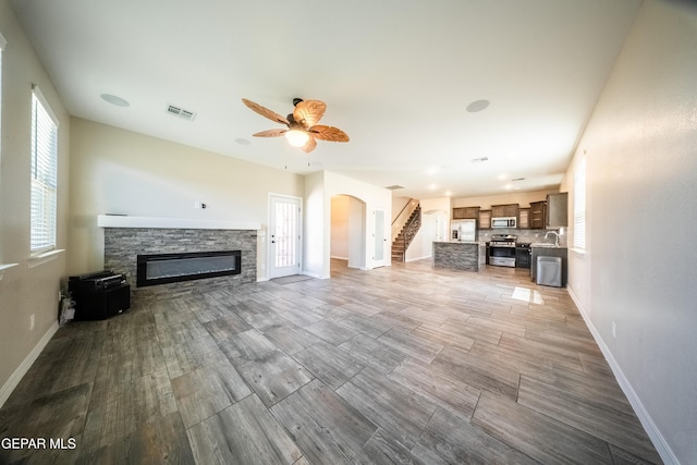 12320 Desert Path Ct, El Paso, TX 79938 - unfurnished living room with arched walkways, a stone fireplace, and baseboards