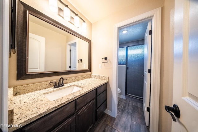 12320 Desert Path Ct, El Paso, TX 79938 - bathroom with vanity, toilet, wood finished floors, baseboards, and an enclosed shower