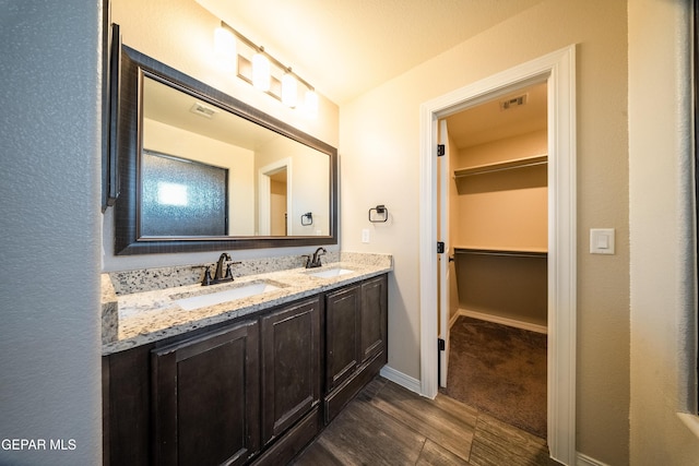 12320 Desert Path Ct, El Paso, TX 79938 - bathroom featuring double vanity, wood finished floors, a walk in closet, and baseboards