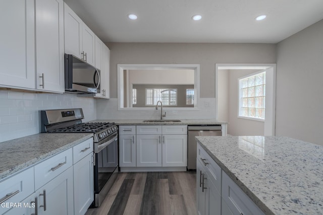3427 Hamilton Ave, El Paso, TX 79930 - kitchen with stainless steel appliances, a sink, dark wood finished floors, light stone counters, and white cabinetry