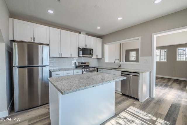 3427 Hamilton Ave, El Paso, TX 79930 - kitchen with appliances with stainless steel finishes, a sink, decorative backsplash, a center island, and light wood finished floors